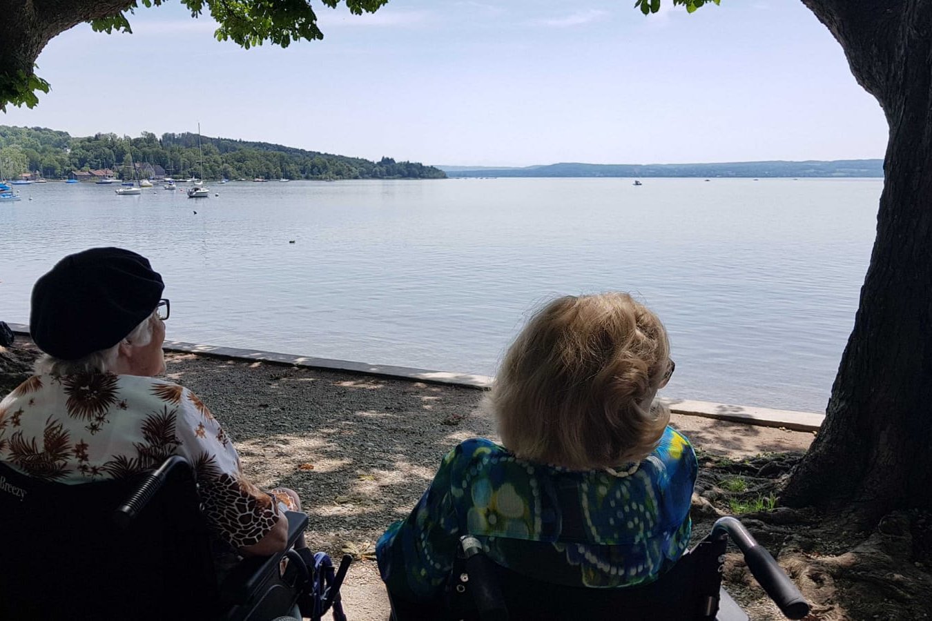 Zwei Seniorinnen im Rollstuhl schauen auf einen See