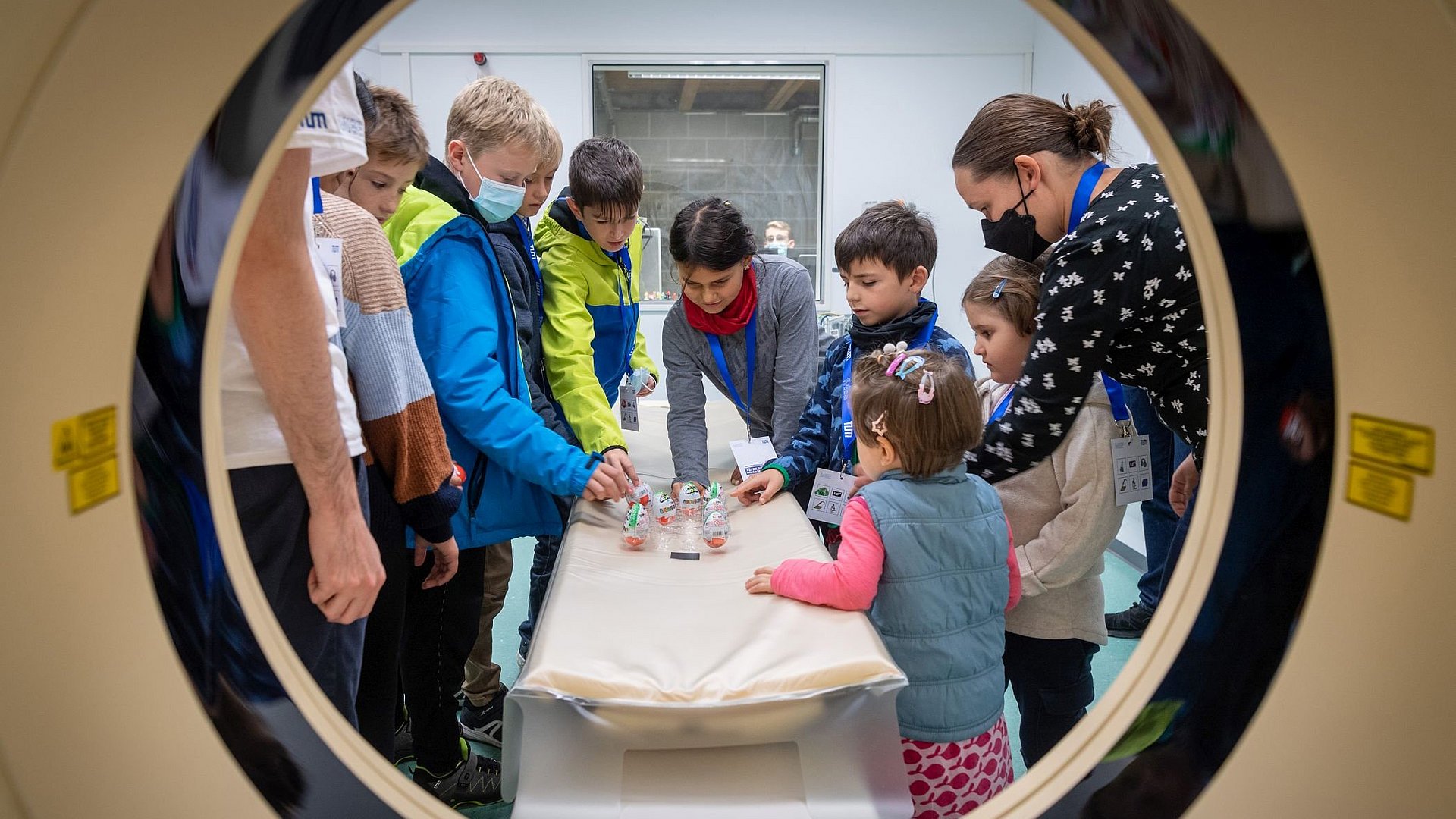 Eine Gruppe Kinder vor einem CT-Gerät, die Überraschungseier untersucht