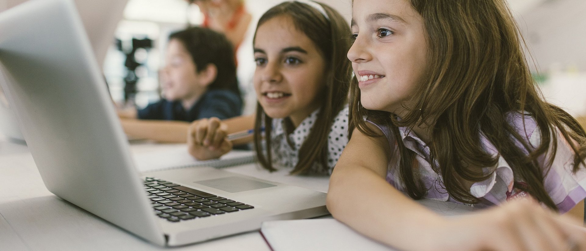 Schülerinnen und Lehrerin an einem Tablet