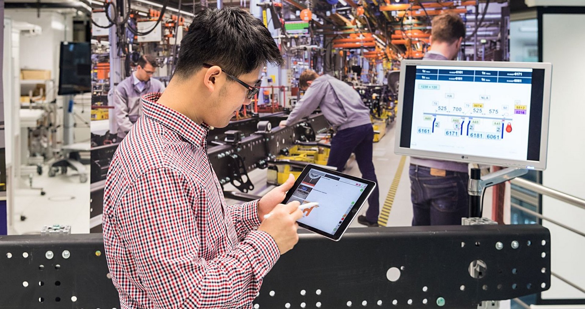 Digitalisierung in der Industrie Wissenschaftler mit Pad vor Produktionshalle am TUM Institut für Werkzeugmaschinen und Betriebswissenschaften.