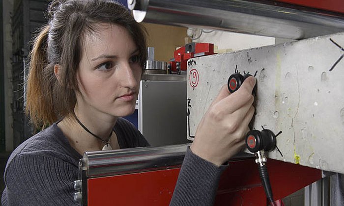 Technician sticks ultrasound sensors onto a concrete beam. (Picture: Werner Bachmeier / TUM)