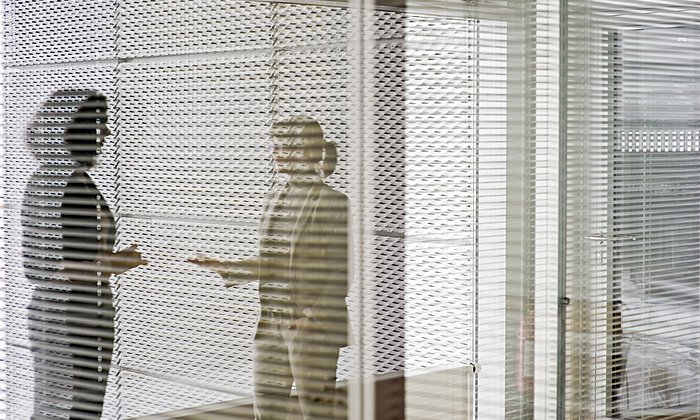 Two women in conversation behind a screen