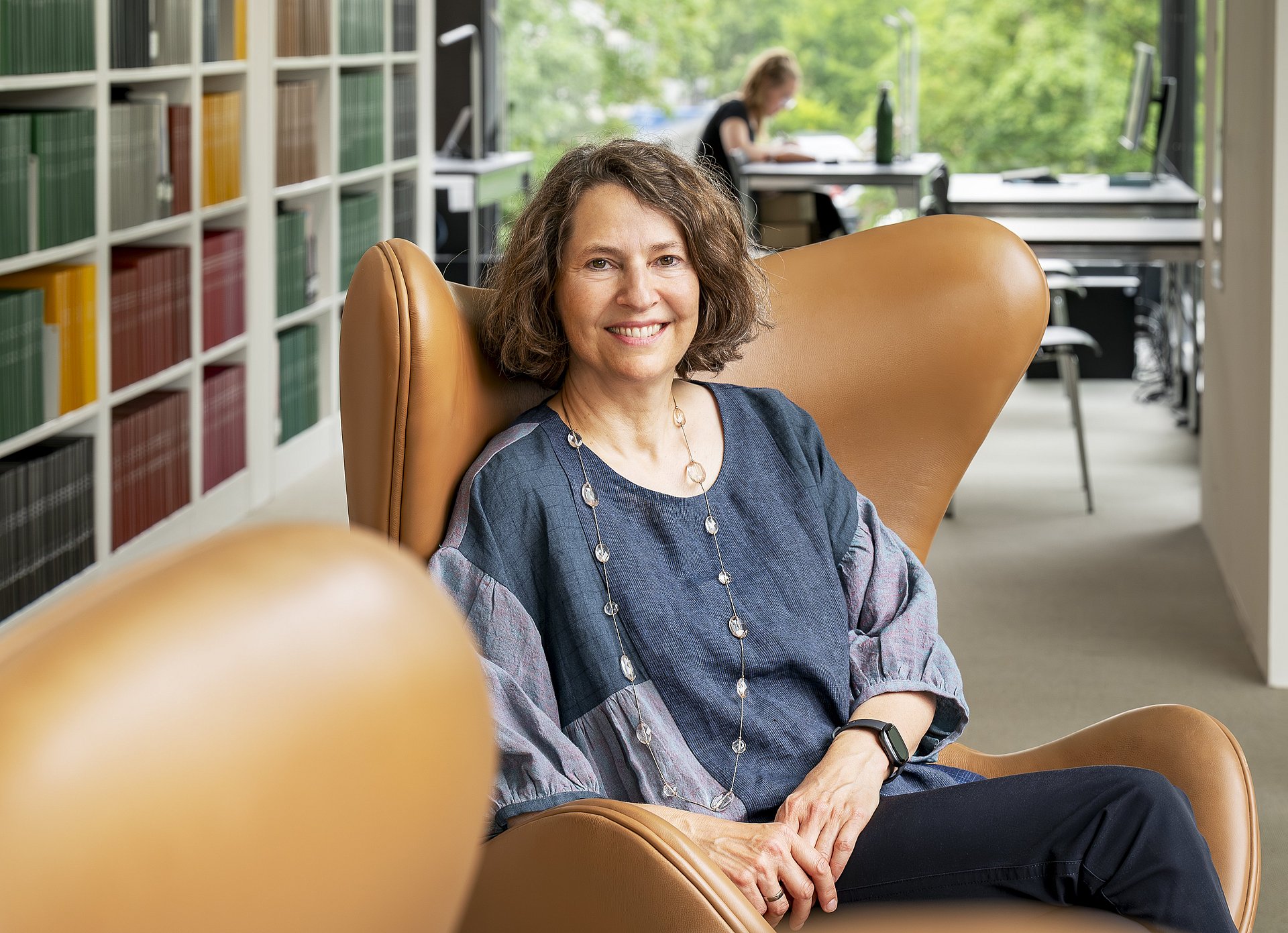 the head of the TUM University Library Caroline Leiss sits in front of a bookshelf