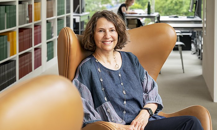 the head of the TUM University Library Caroline Leiss sits in front of a bookshelf