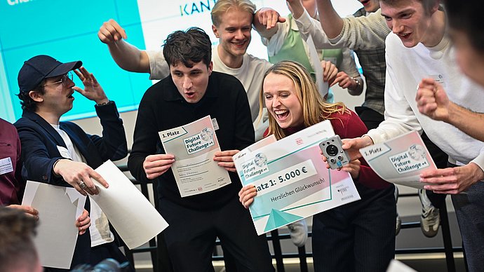 Die jubelnden Mitglieder des Teams "EduPin" mit den Urkunden für den ersten Platz bei der Digital Future Challenge und einem Prototypen des Pins