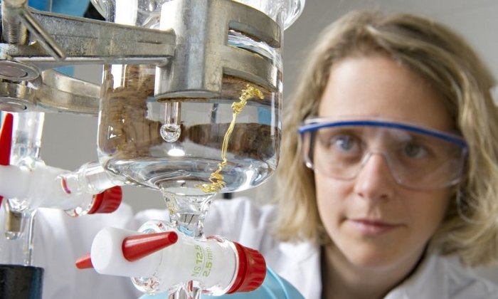 Female chemist wearing safety goggles working on an experiment in the lab.