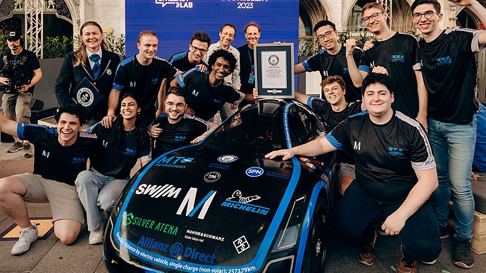 Students stand around a test vehicle celebrating their victory.