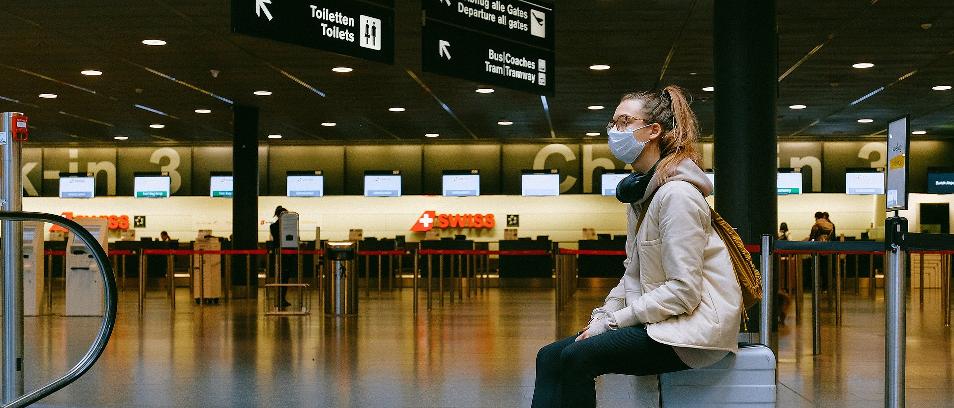 Woman with mouth-nose protection in empty airport terminal