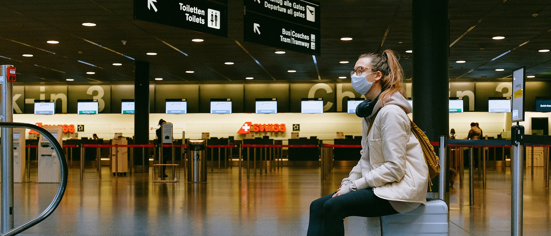 Frau mit Maske in leerem Flughafenterminal