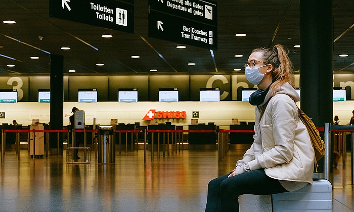 Woman with mouth-nose protection in empty airport terminal