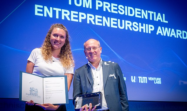 Vizepräsident Prof. Gerhard Kramer verleiht den TUM Presidential Entrepreneuship Award an Flora Geske, Gründerin des Start-ups SUMM AI.