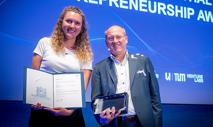 Vizepräsident Prof. Gerhard Kramer verleiht den TUM Presidential Entrepreneuship Award an Flora Geske, Gründerin des Start-ups SUMM AI.