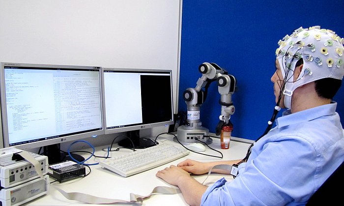 A researcher is connected to a computer via a brain-computer-interface.Gehirn-Rechner-Schnittstelle mit einem Rechner verbunden.