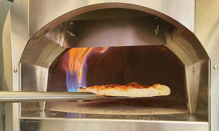Eine Pizza wird im Steinofen gebacken.