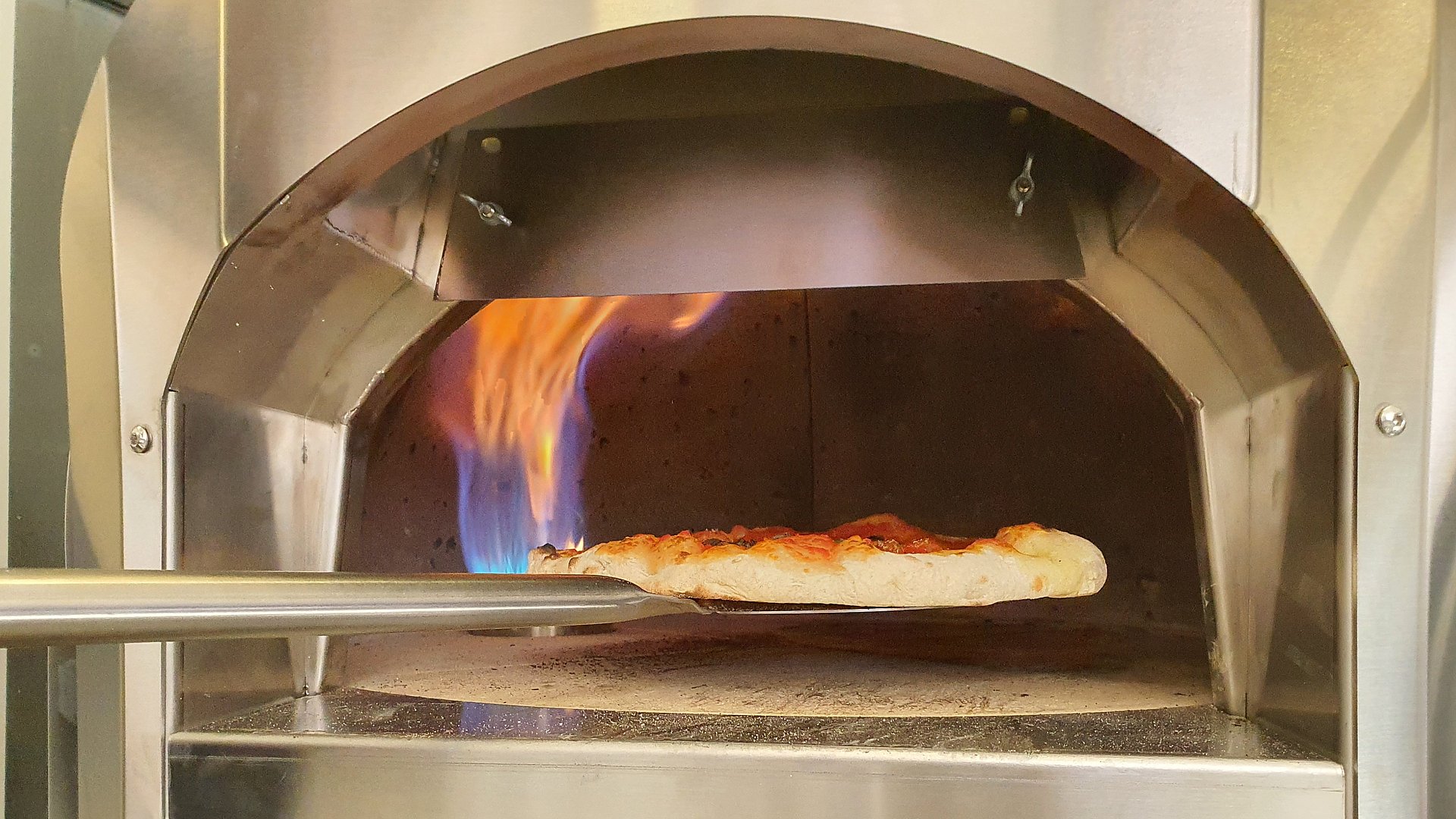 Eine Pizza wird im Steinofen gebacken.