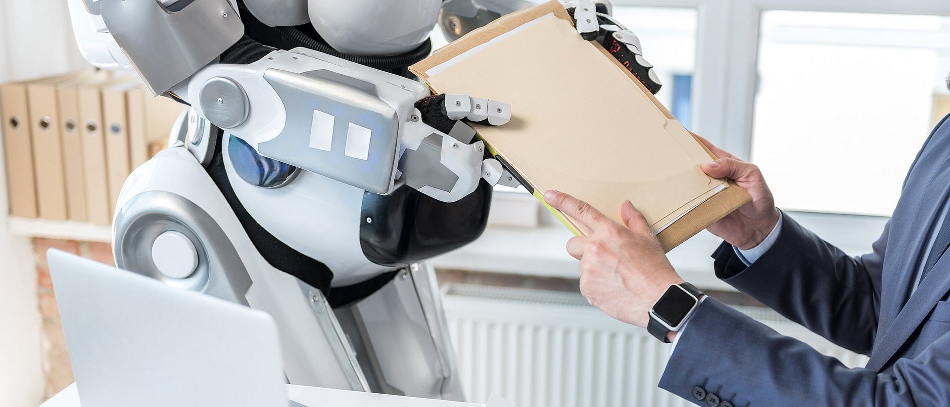 A man hands documents to a robot.