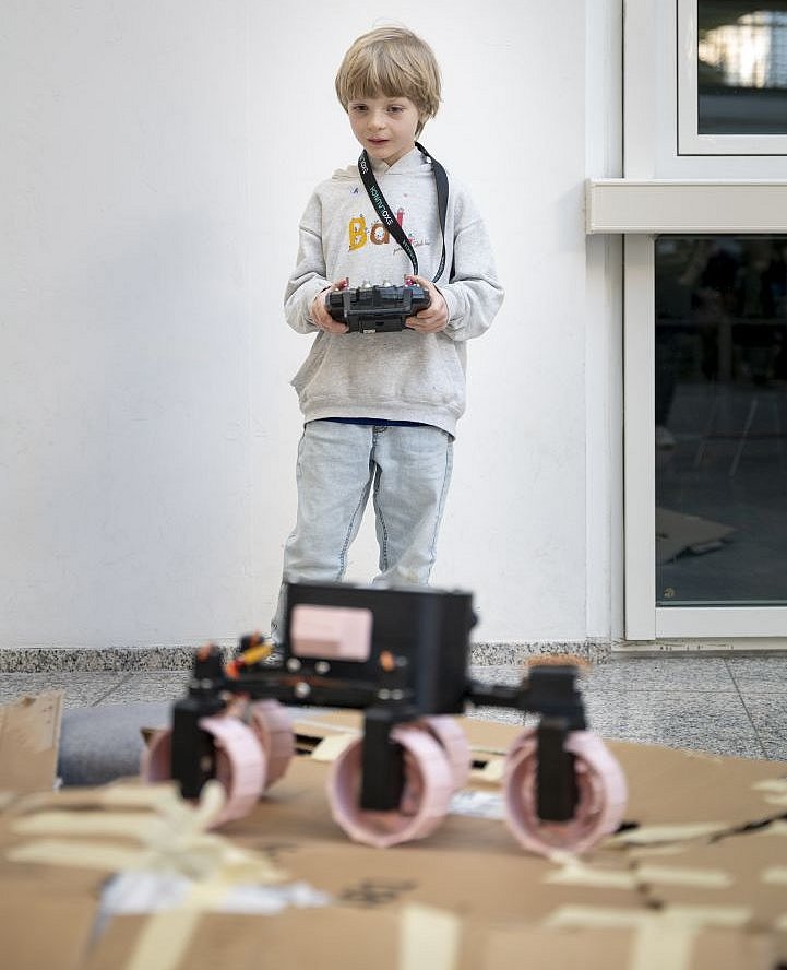 A boy controls a model of a lunar rover
