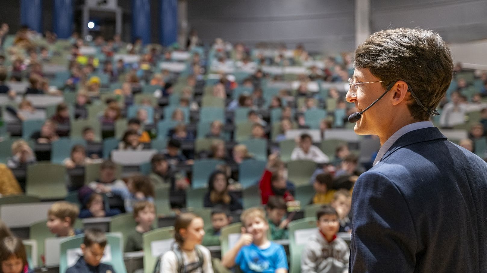 Prof. Reiss stands in front of children in a lecture hall