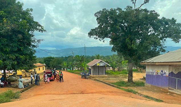 Eine ländliche Straße in Ghana mit Häusern und Menschen