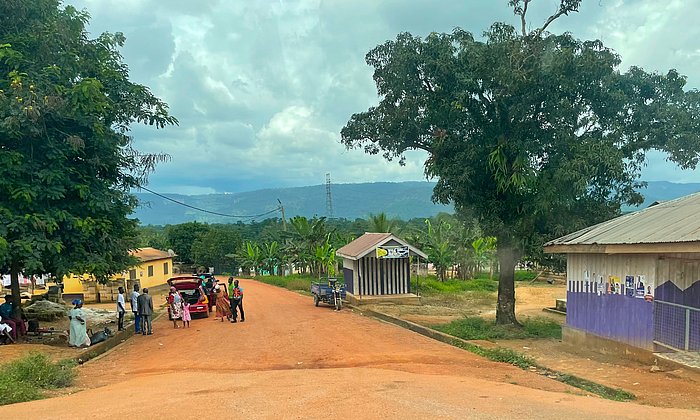 Eine ländliche Straße in Ghana mit Häusern und Menschen