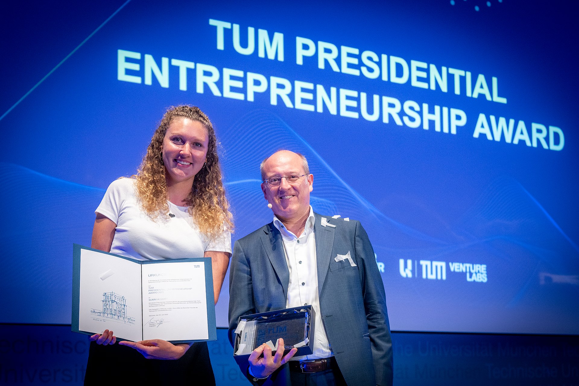 Flora Geske, Gründerin des Start-ups SUMM AI, nimmt den Presidential Entrepreneurship Award von  Vizepräsident Prof. Gerhard Kramer entgegen.