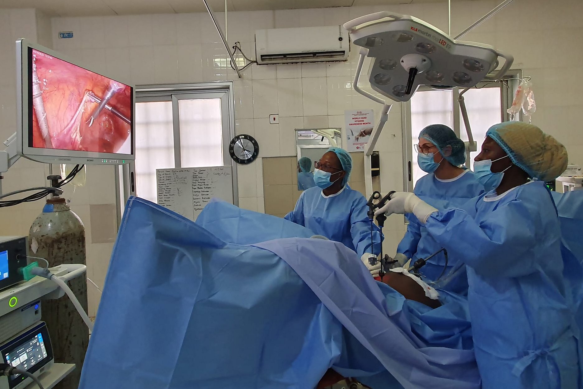 Zwei Ärztinnen und eine OP-Schwester operieren und betrachten das Innere der Patientin auf einem Bildschirm