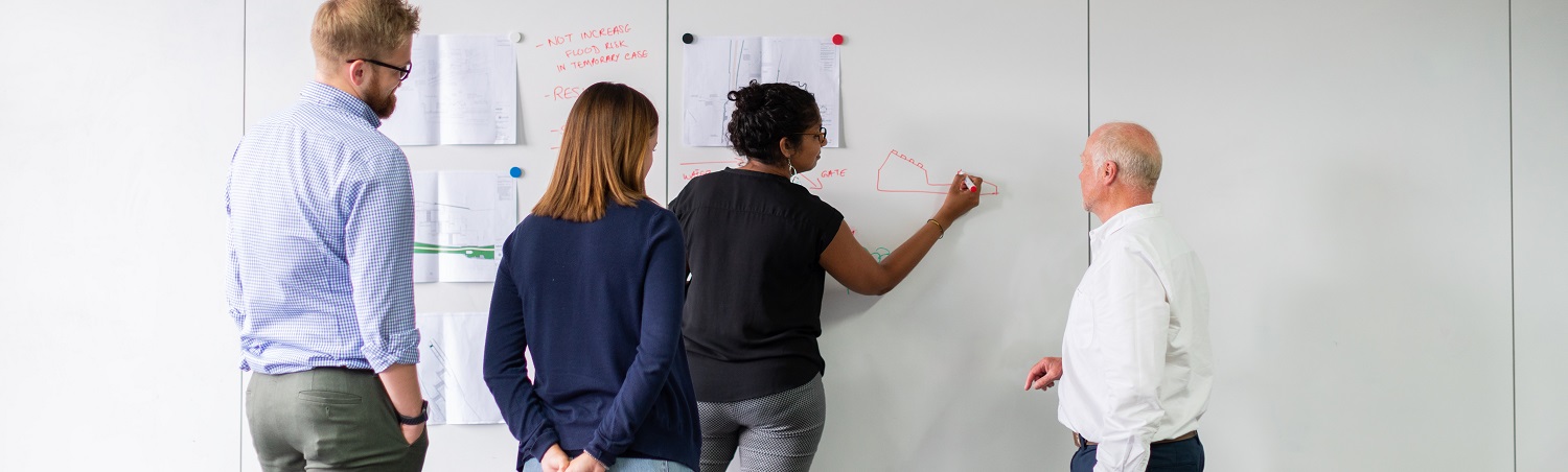 Vier Personen arbeiten an einem Whiteboard Vier Personen arbeiten an einem Whiteboard
