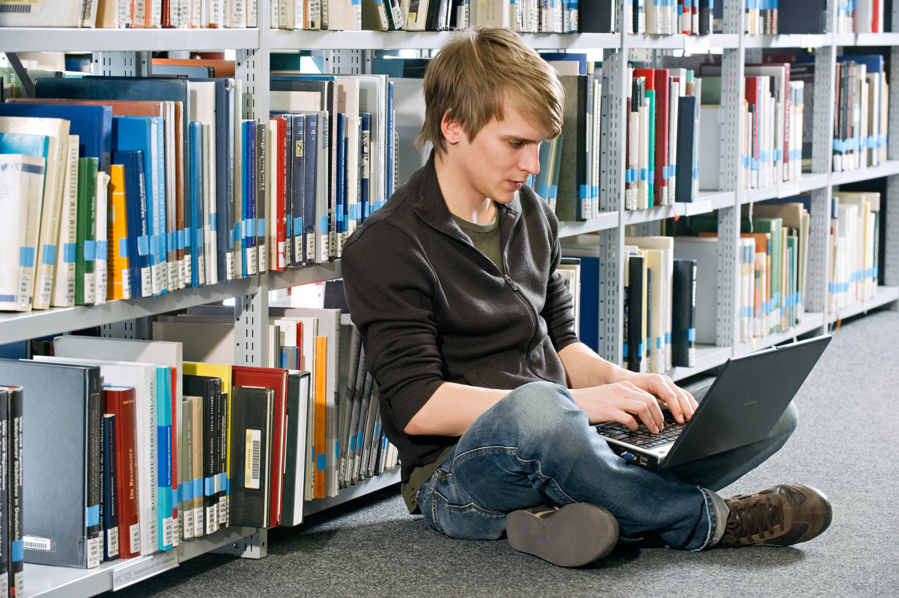 Student sitting in front of bookshelf