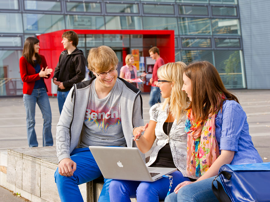 Drei Studierende mit Laptop