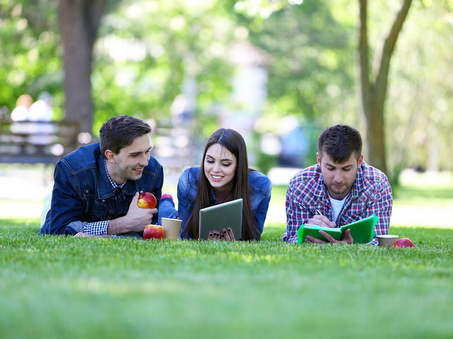 Three students lying on the lawn (Photo: Africa Studio/Fotolia)