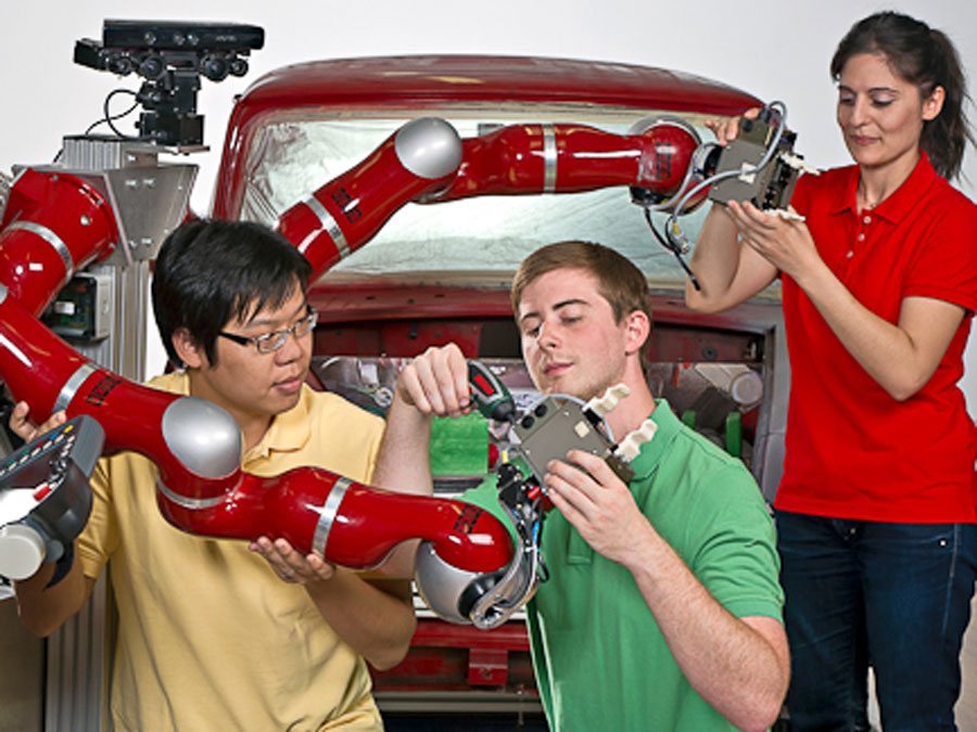 Young researchers working at a robot.