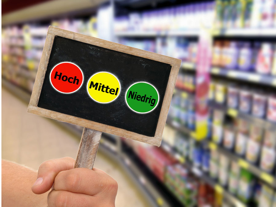 Hand hält Tafel mit einer Verbraucher-Ampel in einem Supermarkt