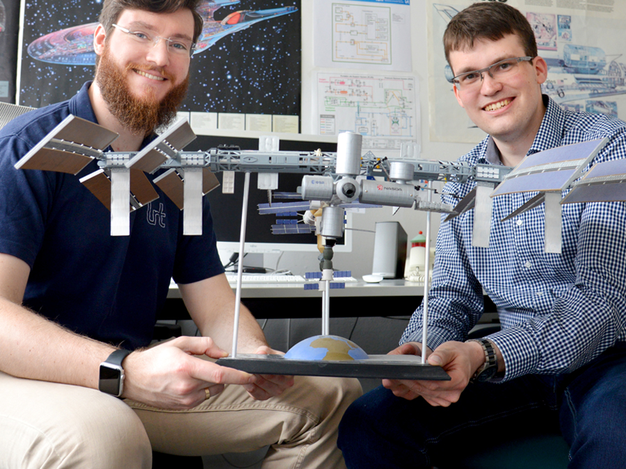 Claas Olthoff (left) and Daniel Pütz are holding a model of the International Space Station.