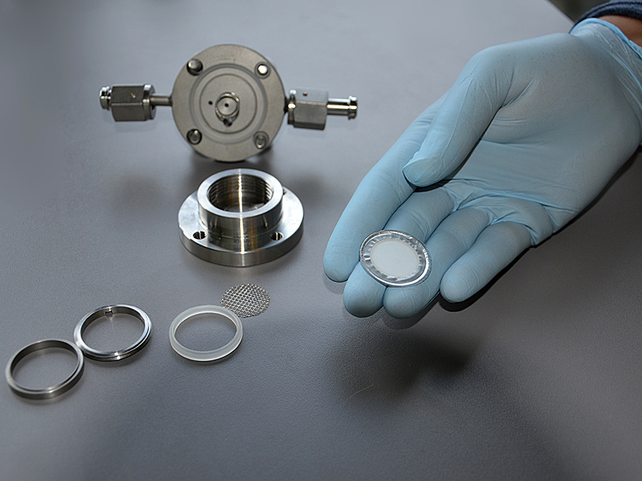 A glass ceramic membrane, coated with aluminum and plastic, allows only lithium ions to pass through. It is impermeable to all other components of the electrolyte fluid - Photo: Monika Weiner / TUM A glass ceramic membrane, coated with aluminum and plastic, allows only lithium ions to pass through. It is impermeable to all other components of the electrolyte fluid - Photo: Monika Weiner / TUM