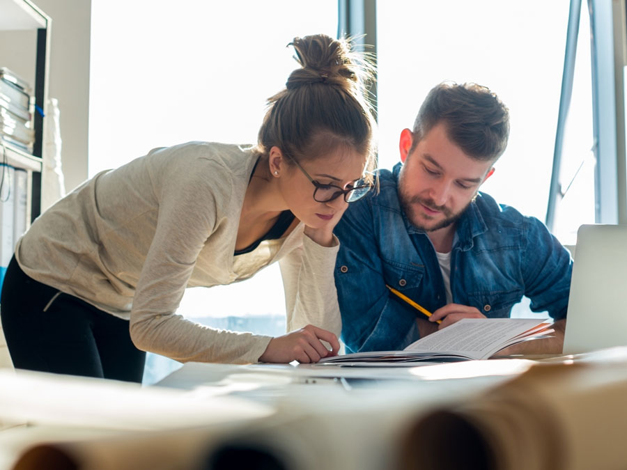 Eine Frau und ein Mann konzentrieren sich im Büro auf einen Text