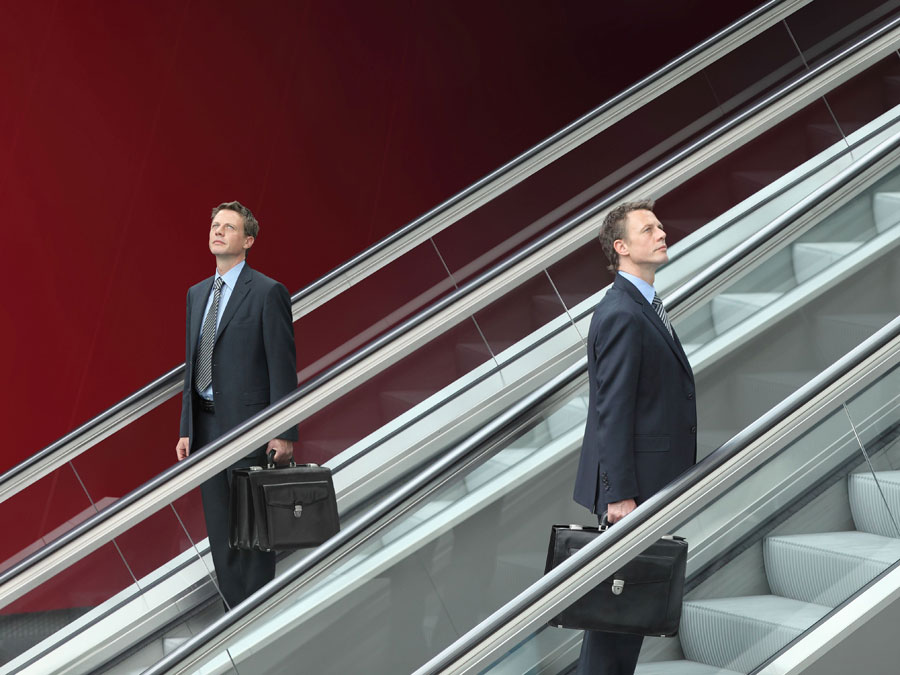 Men in suits on escalators in opposite directions