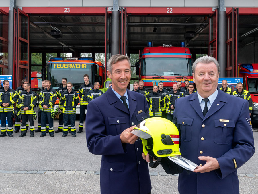 Kurt Franz und Jürgen Wettlaufer vor Mitarbeitern und Fahrzeugen der TUM-Feuerwehr. (Bild: A. Heddergott / TUM)