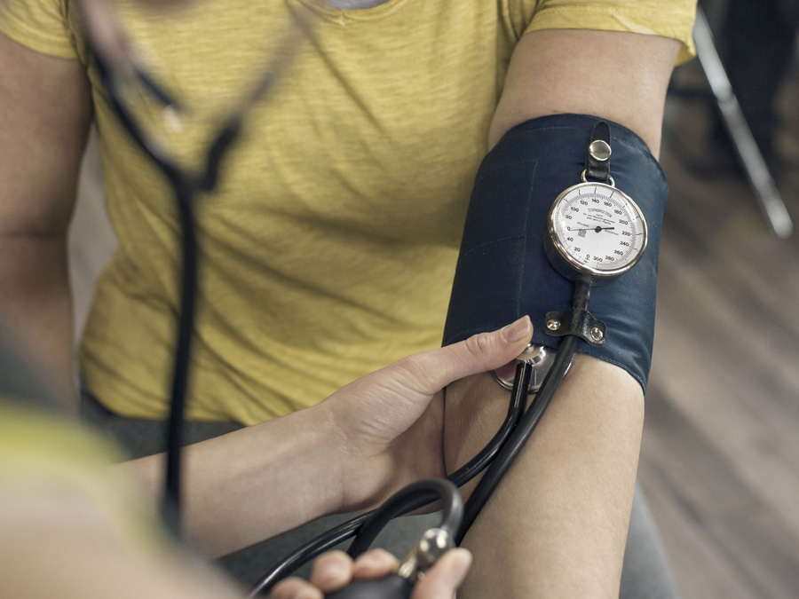 One person measuring blood pressure on another's arm.