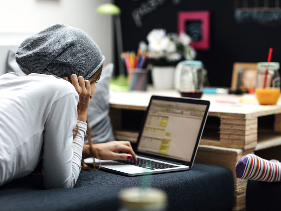 Jugendliche liegt mit Laptop auf einem Sofa.  (Bild: vgajic / istockphoto.com)