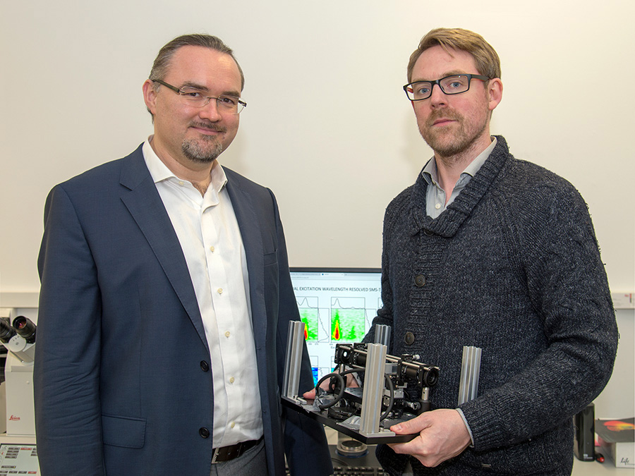 Prof. Dr. Juergen Hauer (left) and first author Erling Thyrhaug with their measuring instrument. In the background, spectra taken with it. (Image: A. Battenberg / TUM)