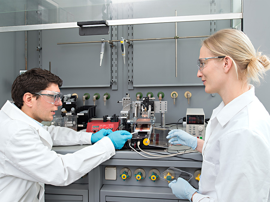 Stephan Pröller (l.) and Dr. Eva M. Herzig in their laboratory. Here they investigate the processes that take place on the molecular scale during the production of organic solar cells.