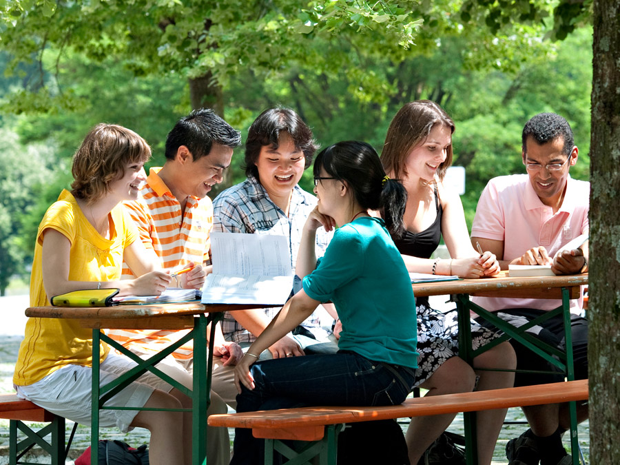 Gruppe Studierender sitzt im Freien und genießt das gute Wetter