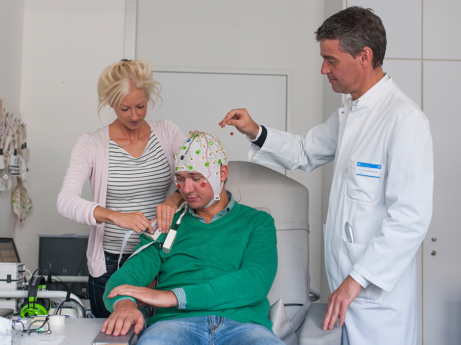 Laura Tiemann, first author of the new study about pain perception, prepares together with Markus Ploner, Heisenberg Professor for Human Pain Research, a volunteer for the EEG-measurements. (Image: K. Bauer / TUM)