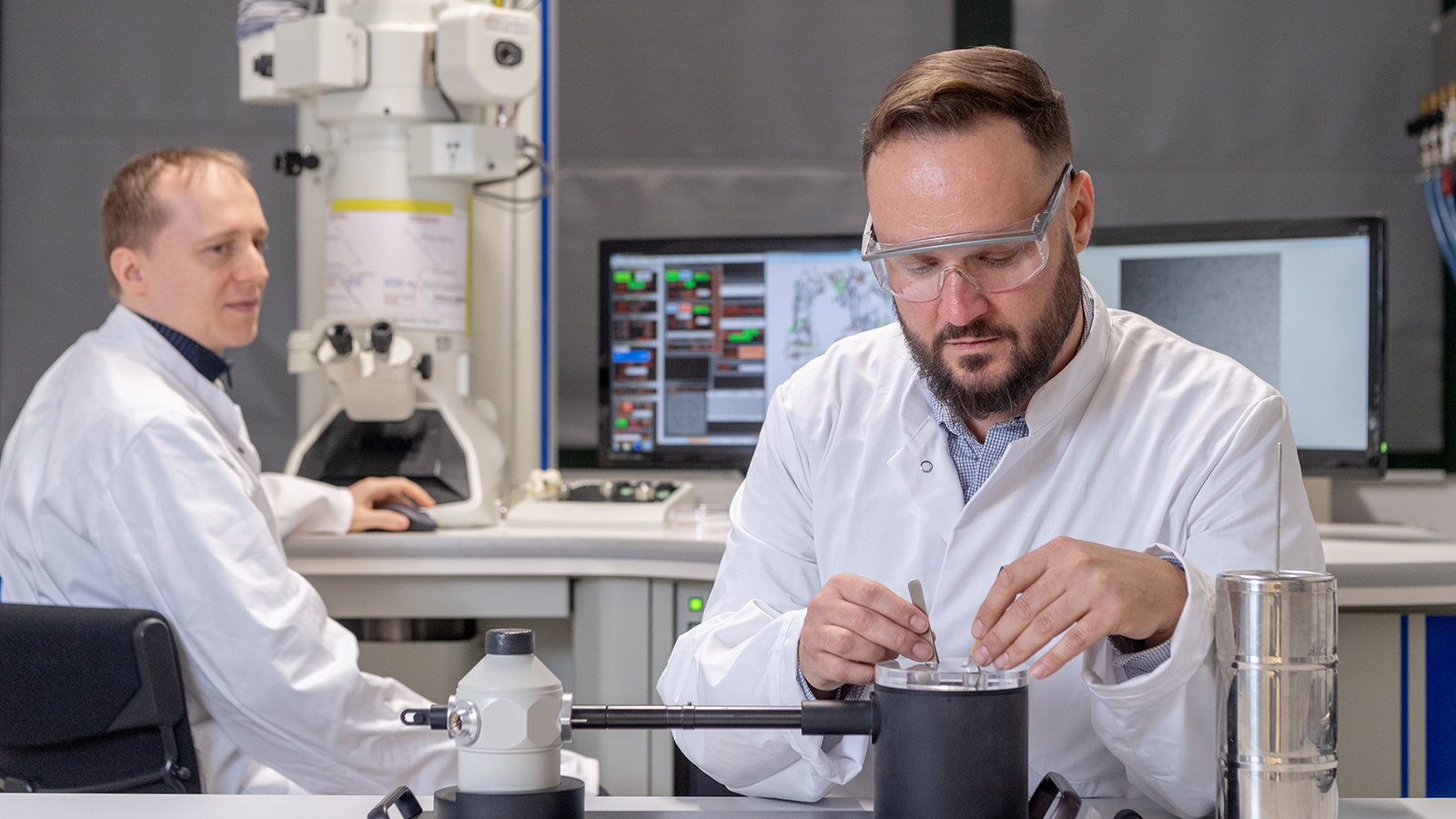Die Erstautoren, Dr. Christoph Kaiser, beim Transfer eines Kryo-Proteinpräparates in einen, mit flüssigem Stickstoff gekühlten Probenhalter und Dr. Carsten Peters am Transmissionselektronenmikroskop.