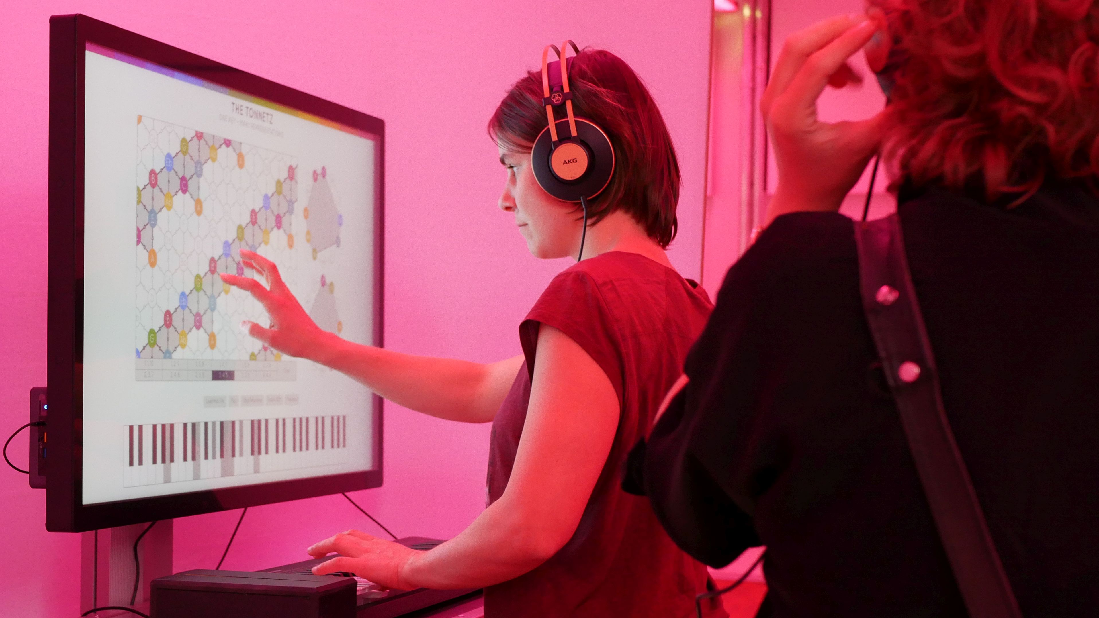 Eine Frau berührt einen Bildschirm in der Ausstellung „La La Lab – Die Mathematik der Musik“.