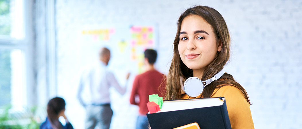 Plug-in-Module In die Kamera blickende Studentin, im Hintergrund ein heller, moderner Seminarraum