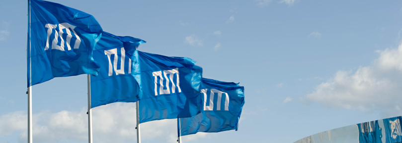 Four blue flags of TUM flying in the wind. Four blue flags of TUM flying in the wind.